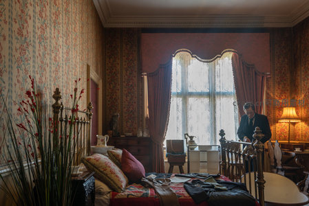 复古卧室窗边，男子整理衣物光影斑驳