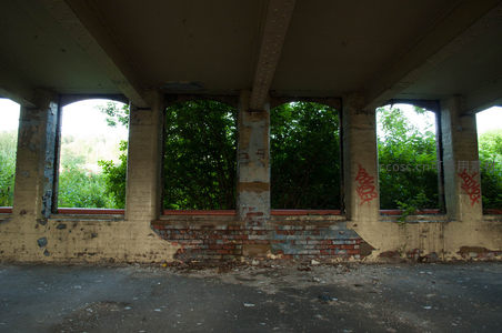废弃厂房拱形窗框外的绿树成荫