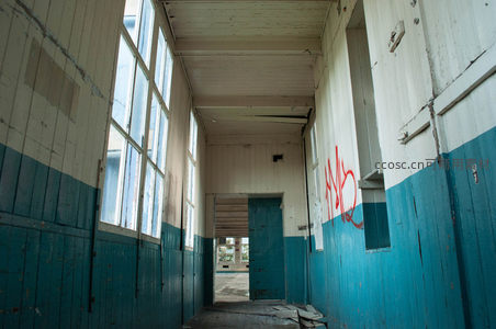 空旷长廊尽头，蓝色墙裙与红色涂鸦