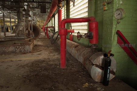 老旧厂房内红色管道与锈蚀容器