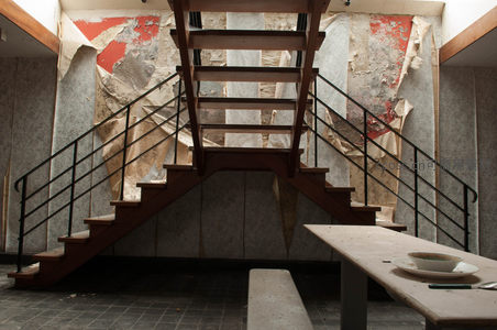 破旧楼梯下空荡餐厅，墙皮剥落显沧桑