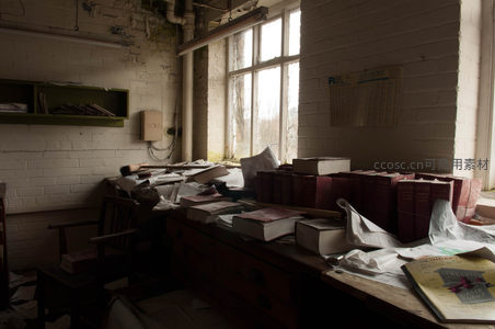废弃办公室书桌堆满旧书，阳光穿透尘埃