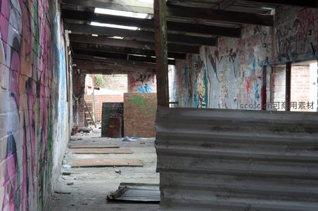 涂鸦密布的工业廊道，木质横梁支撑残破屋顶