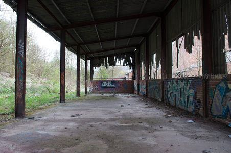 荒废车间通道，彩色涂鸦覆盖砖墙铁柱