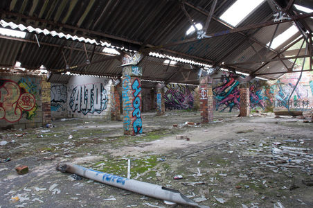 废弃仓库内部，彩绘涂鸦与锈蚀顶棚