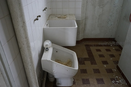 废弃浴室的破败景象，浴缸与便池满是尘埃