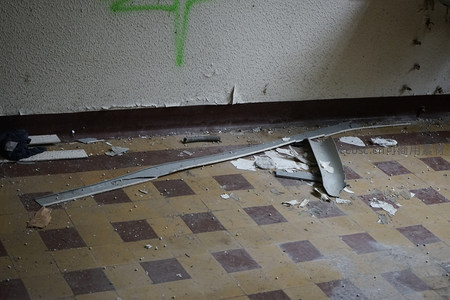 墙边倒伏的金属条与绿色涂鸦