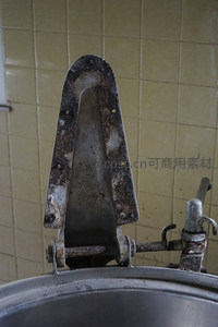 老旧金属闸门锈蚀严重，背景瓷砖泛黄陈旧