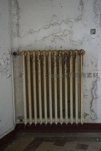 生锈暖气片倚靠在剥落墙边