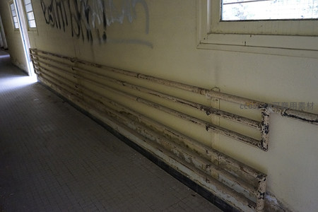废弃走廊里锈蚀管道与涂鸦墙面