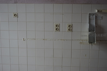 老旧瓷砖墙上的插座与破损痕迹