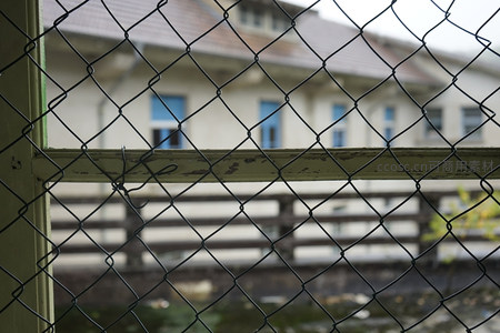 铁丝网后朦胧老建筑的隔离感