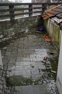 废弃阳台的绿色涂鸦与散落瓦片