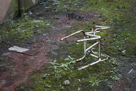 锈蚀助行器倒卧青苔湿地上