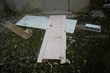 破旧木门倒卧在满是碎玻璃的泥地上