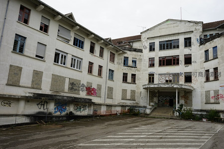 废弃工厂建筑群，墙面涂鸦斑驳，空旷庭院显荒凉