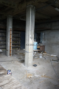空旷厂房内粗壮水泥柱与散落杂物