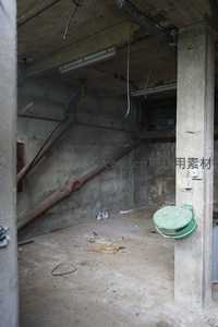 昏暗地下室中的锈蚀管道与绿色井盖