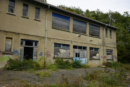荒废厂房侧面，门窗破损显沧桑感