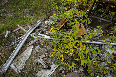 野草丛中散落着废弃金属管与木板残骸