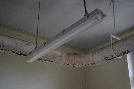 天花板下悬挂的老旧荧光灯与锈蚀管道