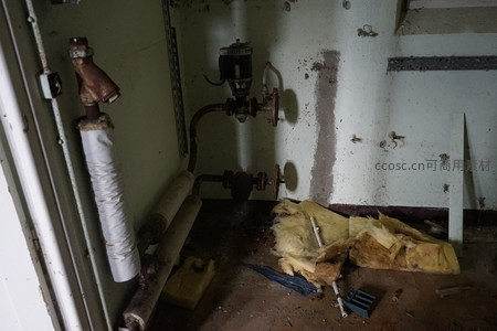 废弃房间内锈蚀管道与散落保温棉