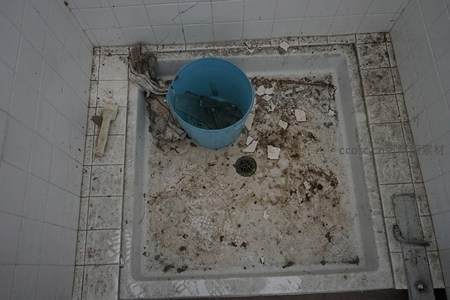 肮脏浴缸内放着蓝色水桶和碎片