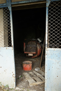 透过铁网门窥见深处废弃的红色机械