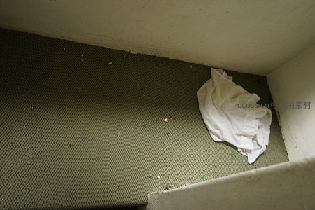 楼梯角落的绿色地毯与废弃纸巾