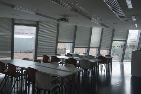 空旷教室静待学子，桌椅整齐映衬窗外城市风景