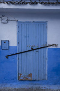 锁闭的蓝色木门与斑驳墙面的静谧