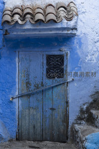 蓝色古城的斑驳木门与陶瓦屋顶