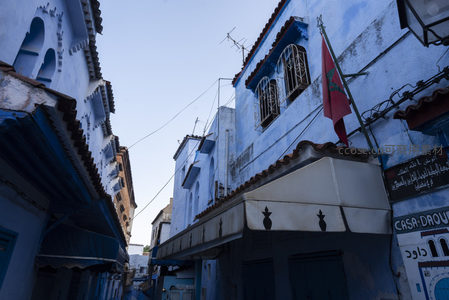 摩洛哥国旗飘扬在蓝色古城的屋檐下