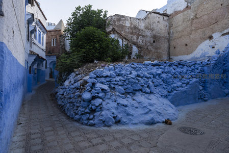 蓝墙环绕的幽深小径，石堆与绿植点缀古老街景
