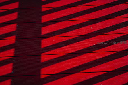 阳光斜照在红木板墙上投下条纹阴影