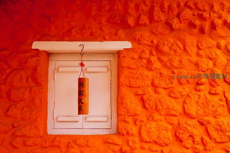 橙色石墙上的白窗与吉祥挂饰