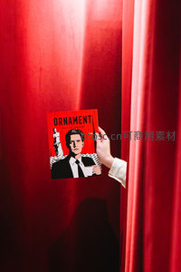 手握电影杂志从红色幕布后探出