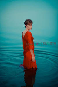 红裙女子伫立碧波水中回眸凝望