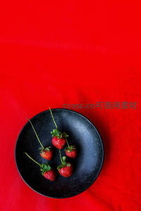 黑盘盛放五颗草莓置于红布之上
