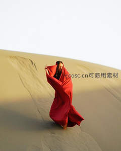沙漠中女子披着红色斗篷漫步沙丘