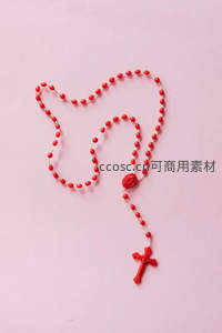 红色念珠在粉色背景上形成心形图案