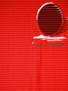 红色波纹金属墙上的圆形通风口特写