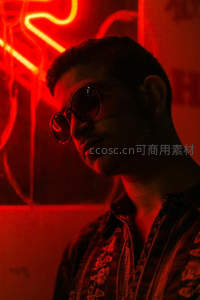 霓虹灯下戴墨镜的时尚男子侧影