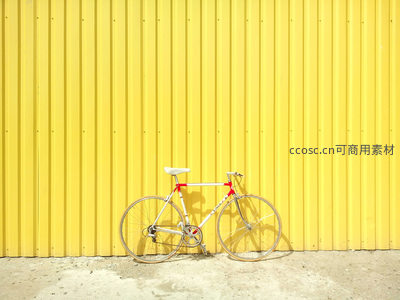 白色公路自行车倚靠明亮黄色墙壁