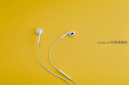 白色耳机静置于明黄背景之上