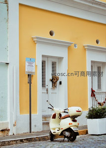 黄色外墙前停着白色踏板车