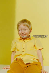 小男孩眨眼微笑，黄色衣裤暖意融融