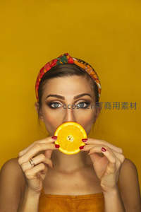 女子手持橙片遮面，黄色背景衬托明媚笑容