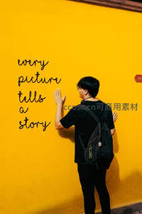 男子触摸写有英文标语的黄色墙壁