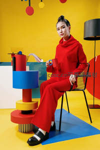 红装女子坐椅持杯凝视镜头